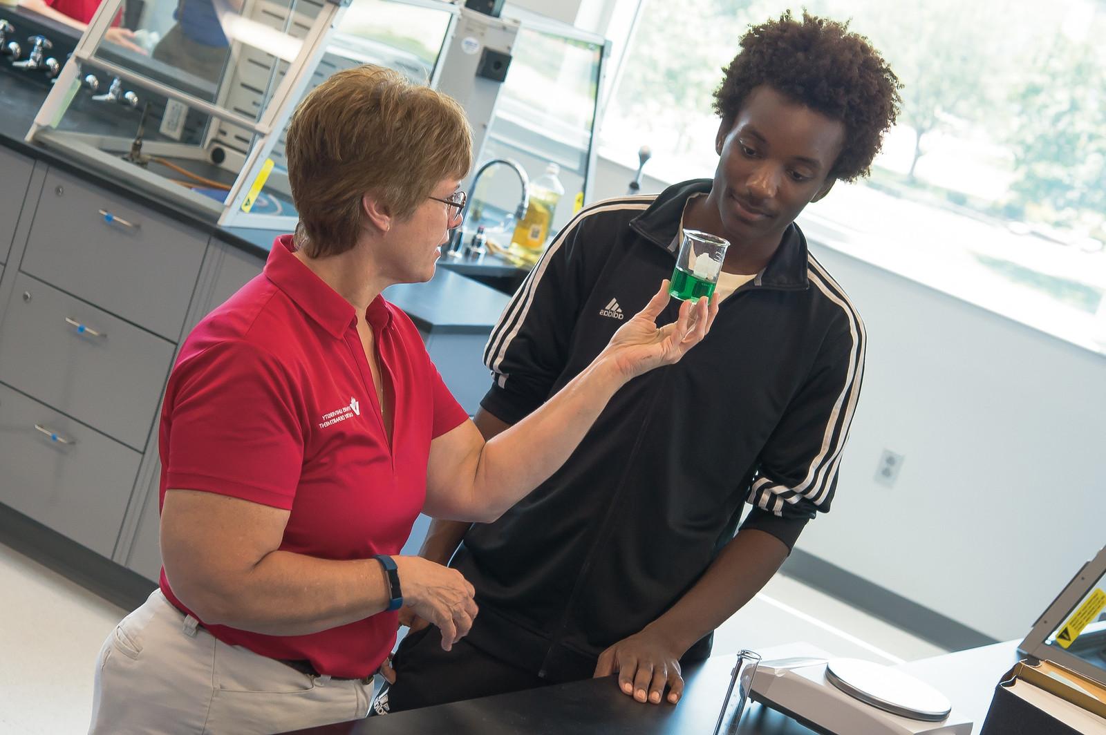 A chemistry teacher showing her student a flask full of chemicals